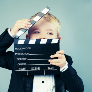 Boy in tuxedo holds a Hollywood slate board